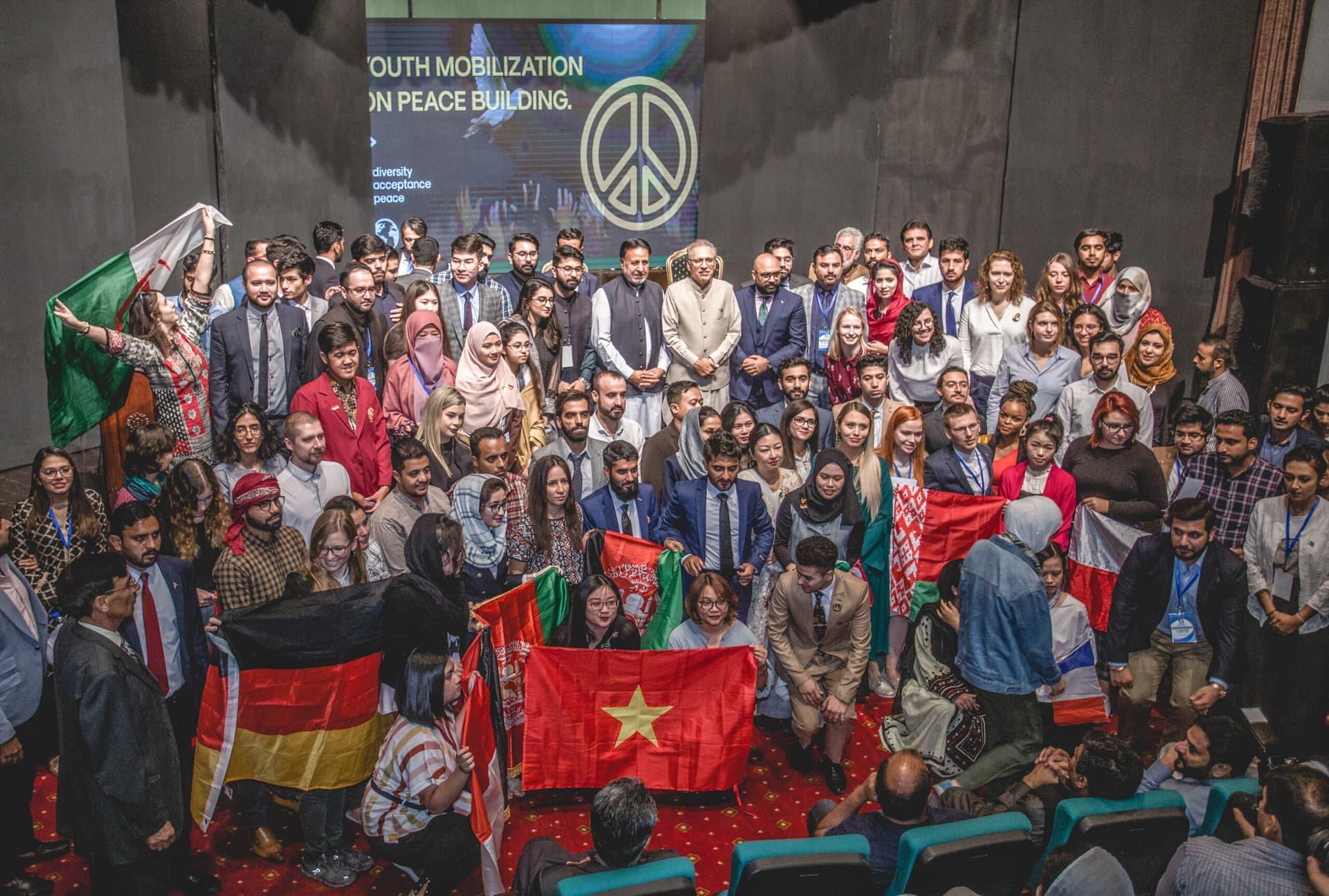 Large community group photo indoors with flags and banners