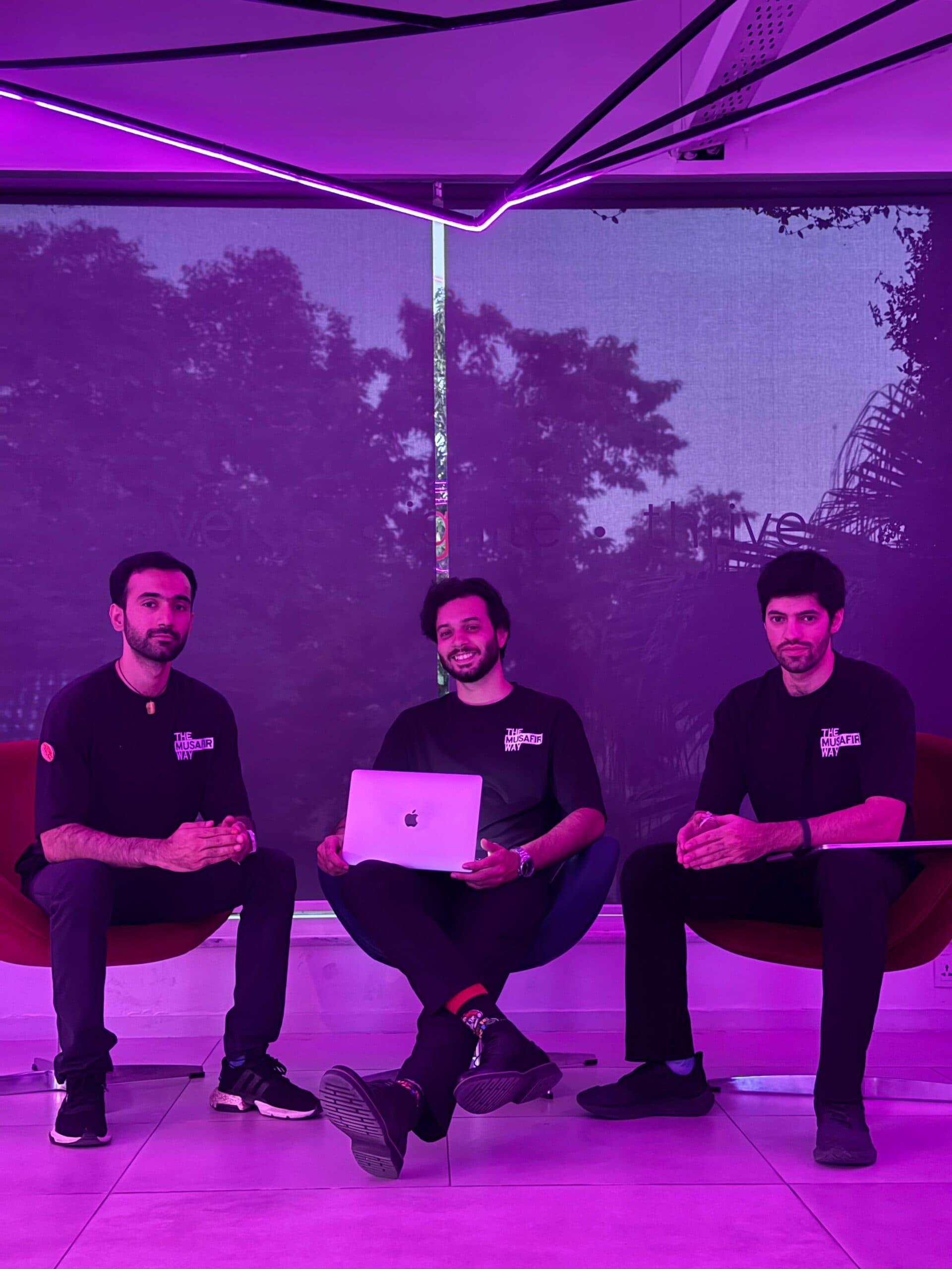 Founders in a purple-lit workspace with a laptop between them