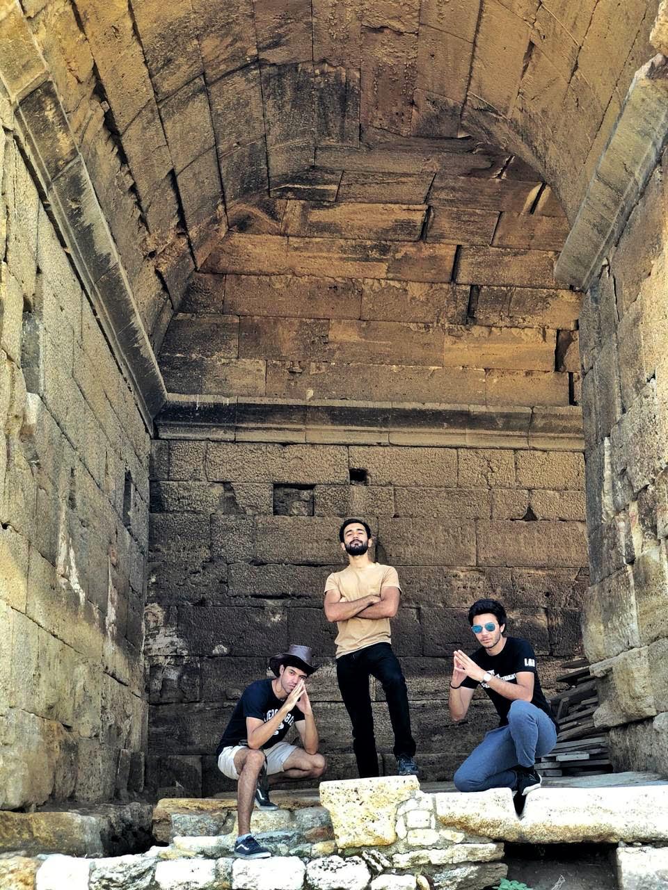 Founders standing inside a historic stone archway with weathered walls