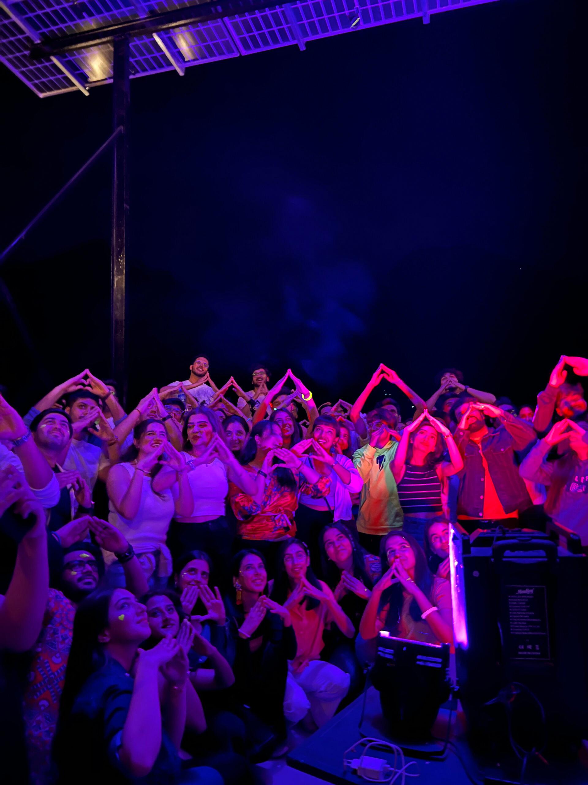 Nighttime crowd with purple lights celebrating together on stage