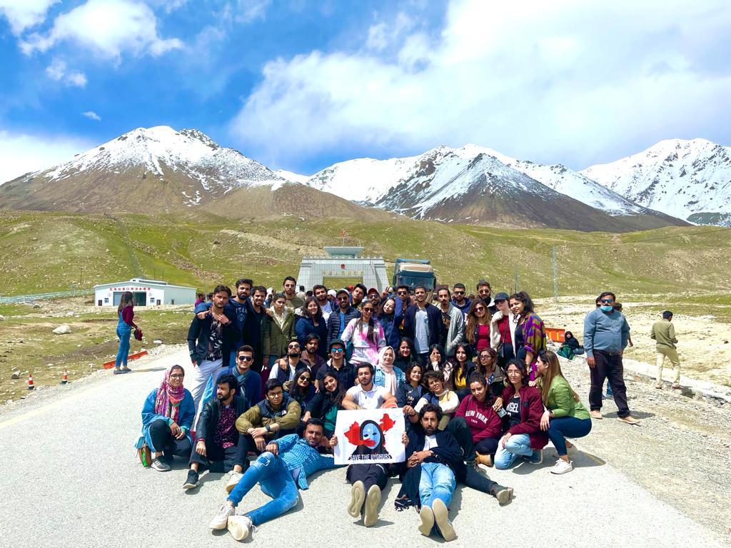 Travel group posing on a mountain road with scenic peaks